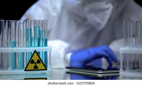 Lab Worker In Gloves Testing Blue Radioactive Liquid In Test Tube, Notes On Tab