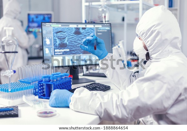 Lab worker preparing test blood for detection of\
coronavirus dressed in ppe. Doctor working with various bacteria\
and tissue, pharmaceutical research for antibiotics against\
covid19.