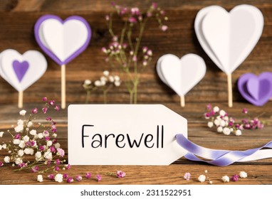 Label With English Text Farewell. Purple And Lilac Decoration And Spring Flower Arrangement. Heart Symbols With Wooden Background.