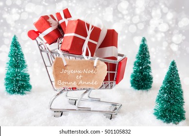 Label With French Text Joyeux Noel Et Bonne Annee Means Merry Christmas And Happy New Year. Trollye With Christmas Presents Or Gifts. Snowy Scenery With Snow And Trees. Sparkling Bokeh Effect.  - Powered by Shutterstock