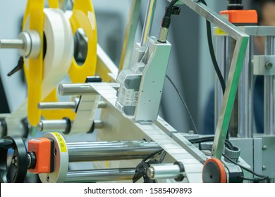 Label printing machine with Roll sticker printing working in a packaging line production in a factory. Automatic label printing system in an automation system in an industrial factory.