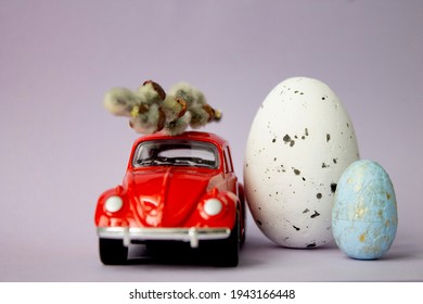 Labinsk. Russia. 25.03.2021 Next To The Red Car Are Two Easter Eggs On A Yellow Background. Easter And Travel Concept. Easter And Family Fun.