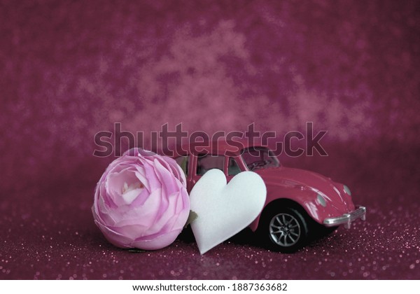 Labinsk, Russia, January 5,\
2021. Beautiful retro car with a peony flower and a heart on a\
background with glitter toning in magenta. Festive atmospheric\
postcard, poster.