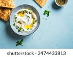 Labneh yogurt cream cheese with olive oil, herbs and zaatar on blue, copy space. Traditional arabian or middle eastern homemade labneh dip with pita bread for breakfast. Arabic Cuisine.