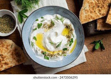 Labneh yogurt cream cheese with olive oil, herbs and zaatar close up. Traditional arabian or middle eastern homemade labneh dip with pita bread. Greek yogurt. Arabic Cuisine. - Powered by Shutterstock