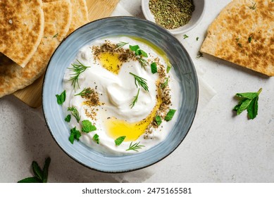 Labneh yogurt cream cheese with olive oil, herbs and zaatar close up. Traditional arabian or middle eastern homemade labneh dip with pita bread for breakfast. Arabic Cuisine. - Powered by Shutterstock