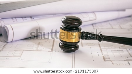 Labor and Construction law concept. Judge gavel on building blueprint plans, close up view.