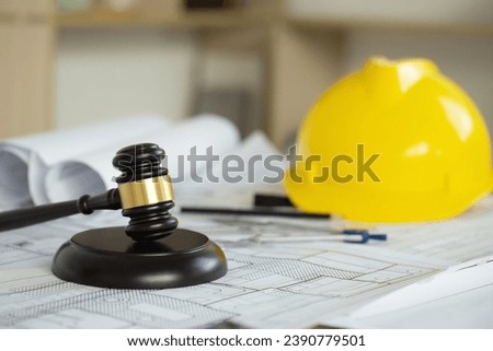 Labor and Construction law concept. judge gavel on building blueprint plans with a yellow safety helmet in the background. law that deals with matters relating to building construction, engineering. 