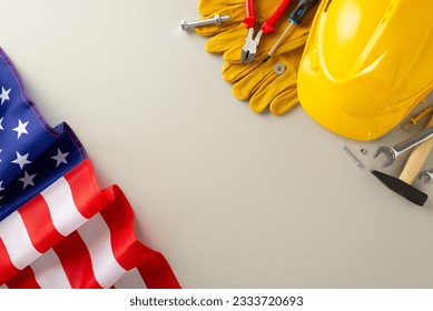 Labor Day celebration with construction professionals: top-view shot, featuring a flag, helmet, gloves, and building instruments on grey isolated background. Ideal for Labor Day content