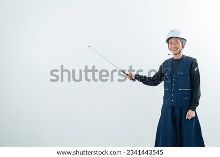 A labor explaining with a pointing stick. A carpenter.