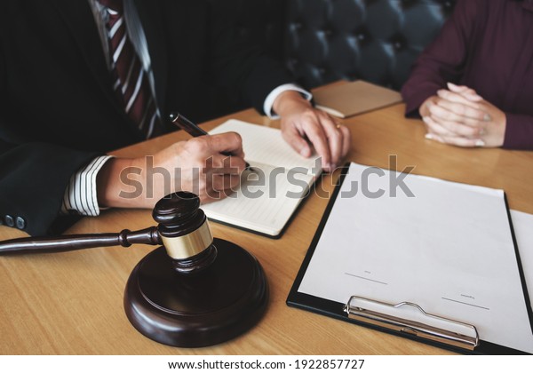  Labor law concept. Lawyer signing legal document with\
Judges gavel \
