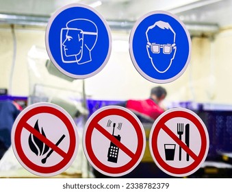 Labor protection signs on the factory door. Open fire, mobile phone, food is prohibited. - Shutterstock ID 2338782379