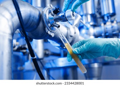 Laboratory assistant inspecting production beer, analysis drink in pipes stainless steel brewing equipment. Concept brewery food industry. - Powered by Shutterstock