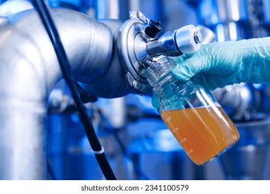 Laboratory assistant inspecting production beer, analysis drink in pipes stainless steel brewing equipment. Concept brewery food industry. - Powered by Shutterstock