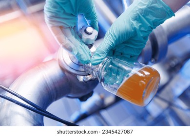 Laboratory assistant inspecting production beer, analysis drink in pipes stainless steel brewing equipment. Concept brewery food industry. - Powered by Shutterstock