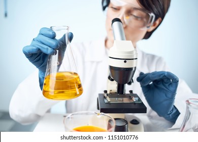  laboratory assistant with a liquid in a flask and a microscope                              
