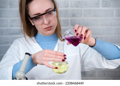 The laboratory assistant mixes two substances in a flask. Conducting chemical experiments. Scientific laboratory. - Shutterstock ID 2208468449