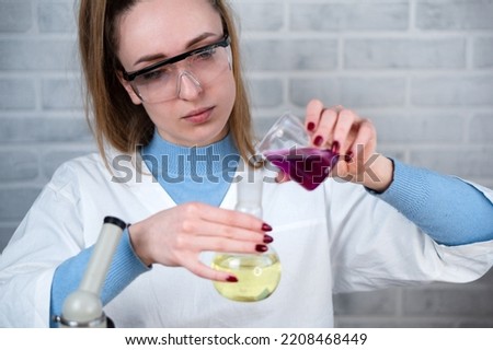 The laboratory assistant mixes two substances in a flask. Conducting chemical experiments. Scientific laboratory.