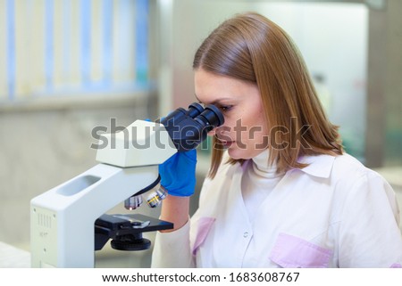 Laboratory assistant working with a microscope in a scientific laboratory. COVID-19. COVID Coronavirus