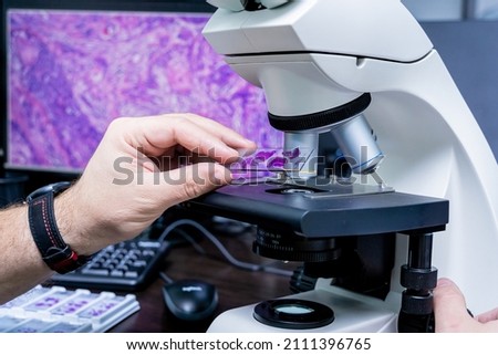 Laboratory assistant works with microscope at the modern laboratory.