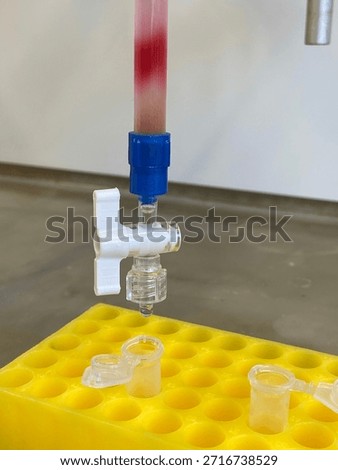 Laboratory burette with red solution drop, close up Science experiment setup in chemistry lab with stopcock and pipette tip; closeup view of liquid titration, measurement and research equipment in lab. 