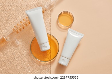 Laboratory concept with orange liquid contained inside of spiral pipe tube and glass petri dishes. Empty label white tubes for cosmetic product promotion