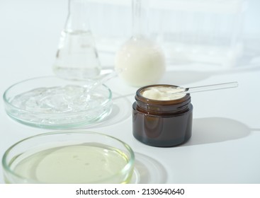 Laboratory Dishes And Glassware On A Lab Table. Fermentation, Fermented Beauty Skin Care. Container With Enzyme Cream Or Solution Or Serum For Anti Age Treatment