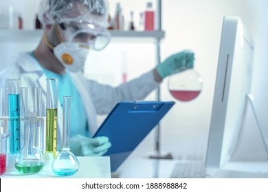 laboratory equipment, supplies, jars, bottles, cylinders, beakers, graduate, test-mixer, medicine-glass. A chemistry laboratory assistant in protective glasses and a mask compares the analysis data 
