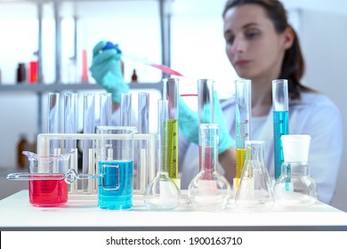 laboratory equipment, supplies, jars, bottles, cylinders, beakers. Lab assistant holding petri dish, pipetting liquid in defocus - Powered by Shutterstock