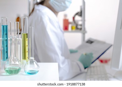 laboratory equipment, supplies, jars, bottles, cylinders, beakers, graduate, test-mixer, medicine-glass. Active lady scientist verifies the data of the document paper plip padfolio in the chemical lab