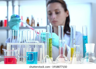 laboratory equipment, supplies, jars, bottles, cylinders, beakers, test-mixer, medicine-glass. Lab assistant holding petri dish, pipetting liquid in defocus