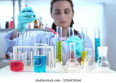 laboratory equipment, supplies, jars, bottles, cylinders, beakers, graduate, test-mixer, medicine-glass. Lab assistant holding petri dish, pipetting liquid in defocus