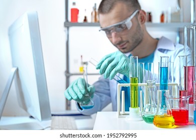 laboratory equipment, supplies, jars, bottles, cylinders, beakers, graduate, test-mixer, medicine-glass. Chemistry lab assistant in protective goggles mixing liquids in glassware and computer.