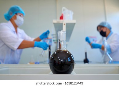 Laboratory Flask With Crude Oil. Lab Test  Petroleum In The Background.