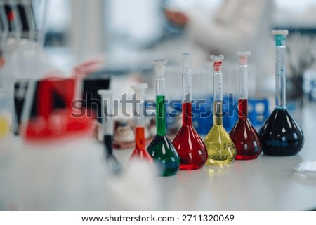 Laboratory flasks containing various colored liquids arranged on a table, used for scientific experiments and chemical analysis