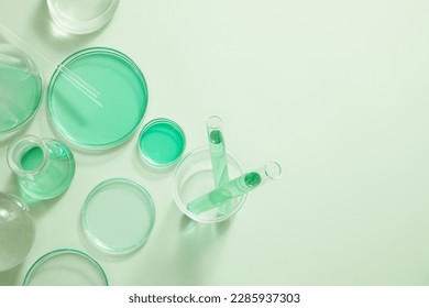 Laboratory glassware filled with green liquid arranged on white background. Blank space for organic beauty product advertising, copy space for text