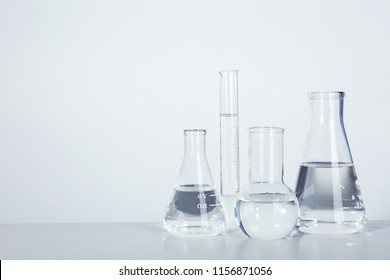 Laboratory Glassware With Liquid On Table Against Light Background. Chemical Analysis