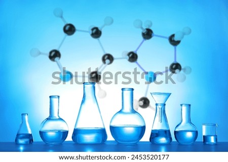 Laboratory glassware and molecule model on blue background