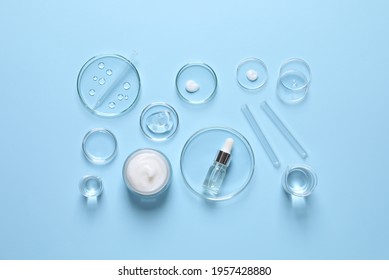 Laboratory glassware and natural ingredients for organic cosmetic product on light blue background, flat lay - Shutterstock ID 1957428880