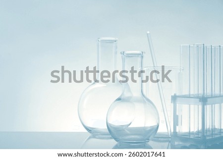 Laboratory glassware on mirror surface against light background, space for text