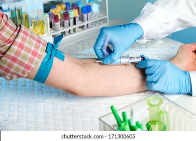 Laboratory with nurse taking a blood sample from patient, in background samples blood and urine tubes
