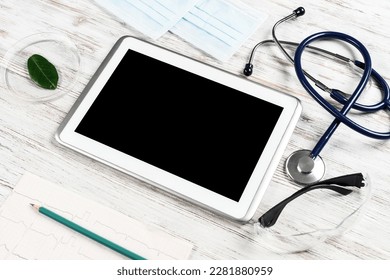 Laboratory patient examination in doctors office. Top view tablet computer, medical mask, stethoscope and cardiogram on wooden desk. Medical diagnostics and examination in modern hospital. - Powered by Shutterstock