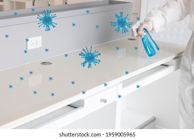 A Laboratory Personal In A White Protective Suit Using Liquid Chemical To Disinfect A Surface Of A Work Bench. 