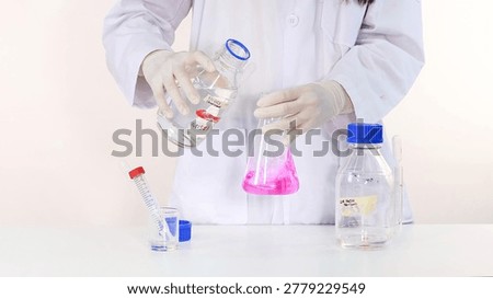 A laboratory professional pours a clear solution into a flask containing a pink indicator.