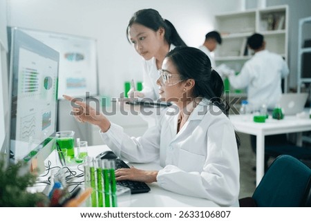 Laboratory research scientists analyzing data results using computer technology and digital charts to support scientific innovation and breakthroughs in healthcare and diagnostics