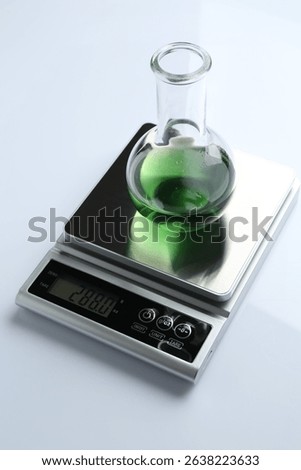 Laboratory scale with flask of sample on white background