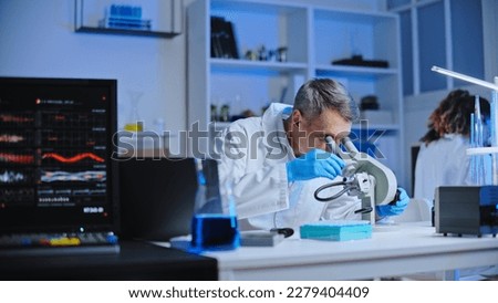 Laboratory scientist examining sample under microscope, conducting research