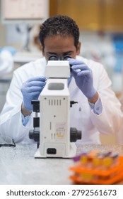 Laboratory scientist using microscope for blood testing and clinical research in a modern medical lab