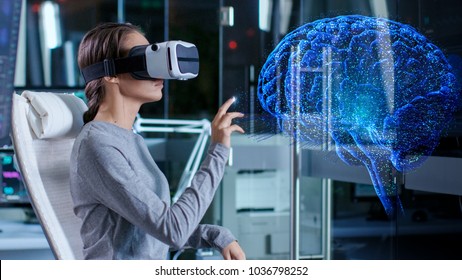 In Laboratory Scientist Wearing Virtual Reality Headset Sitting in a Chair Interacts With Brain Projection Hologram, Showing Neurological Data. Modern Brain Study/ Neurological Research Center.