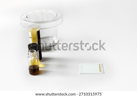 A laboratory setup for Thin Layer Chromatography (TLC) featuring a developing tank, sample solution vials, capillary tubes, and TLC plate with spotted sample ready for analysis.